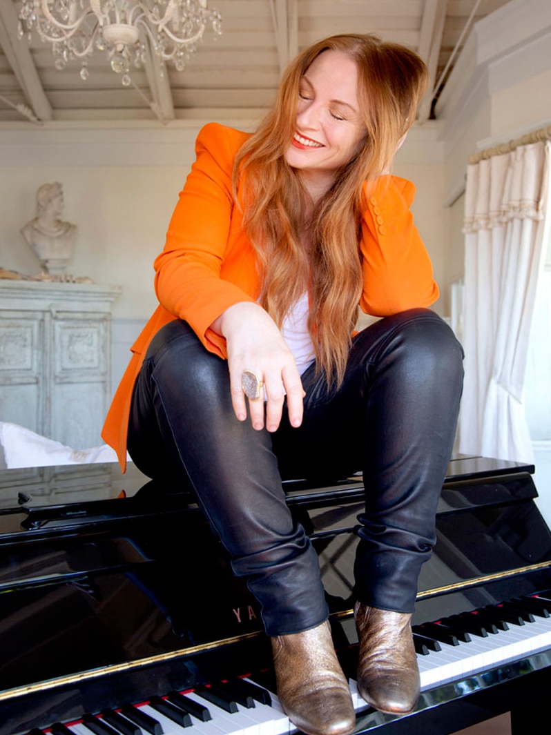 A laughing woman sits on a piano.