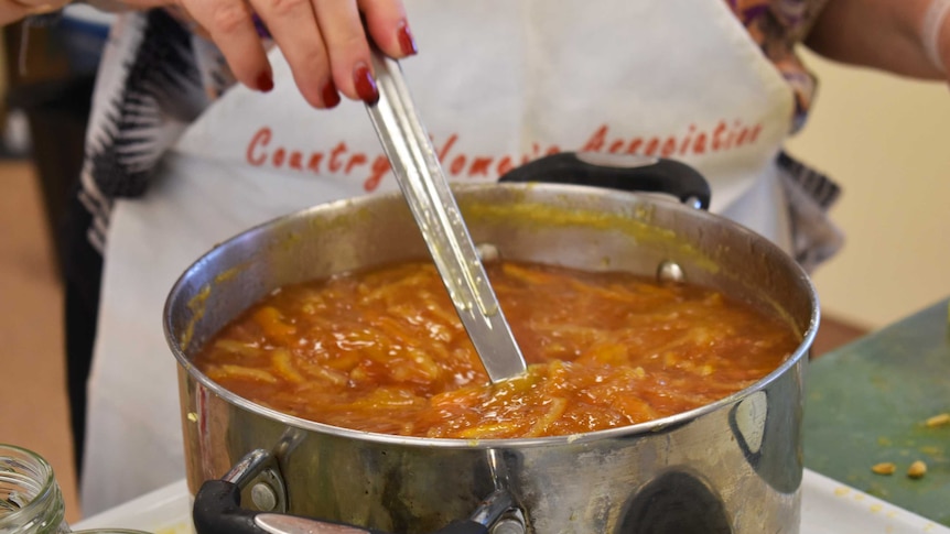 A pot of boiling marmalade being stirred.