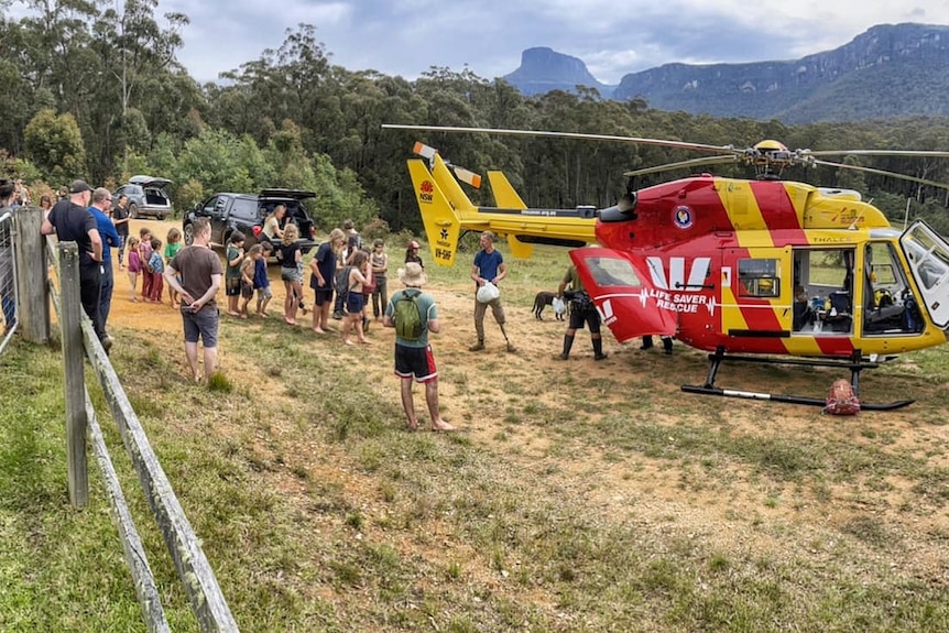 a helicopter on the ground with people standing next to it