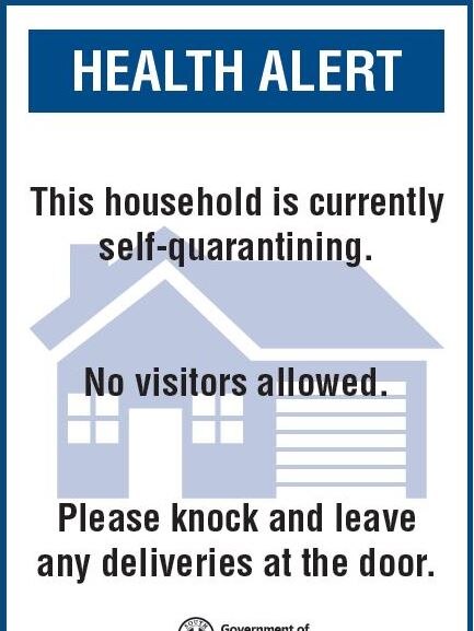 A blue and white sign reading 'Health alert: This house is currently self-quarantining. No visitors allowed.'
