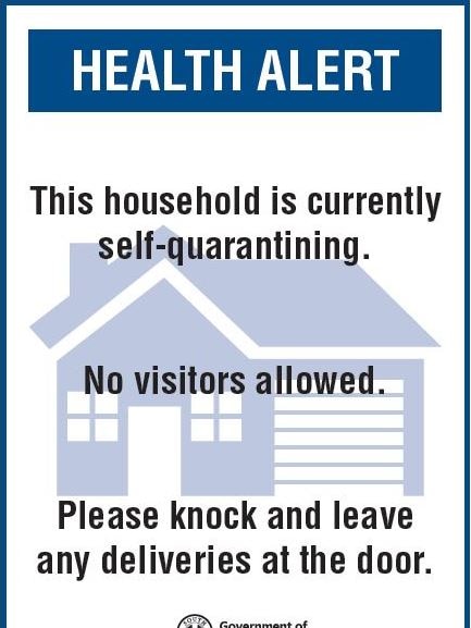 A blue and white sign reading 'Health alert: This house is currently self-quarantining. No visitors allowed.'