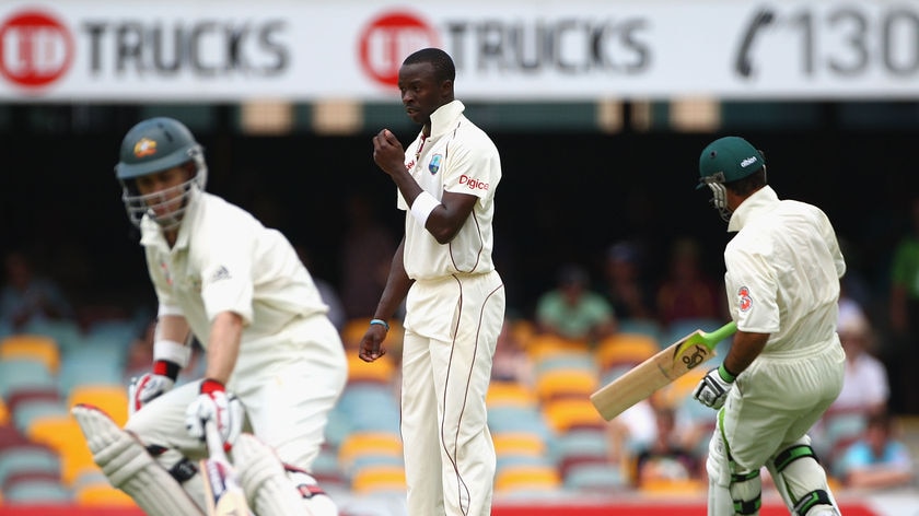 West Indies paceman Kemar Roach looks on as Simon Katich and Ricky Ponting run between wickets.