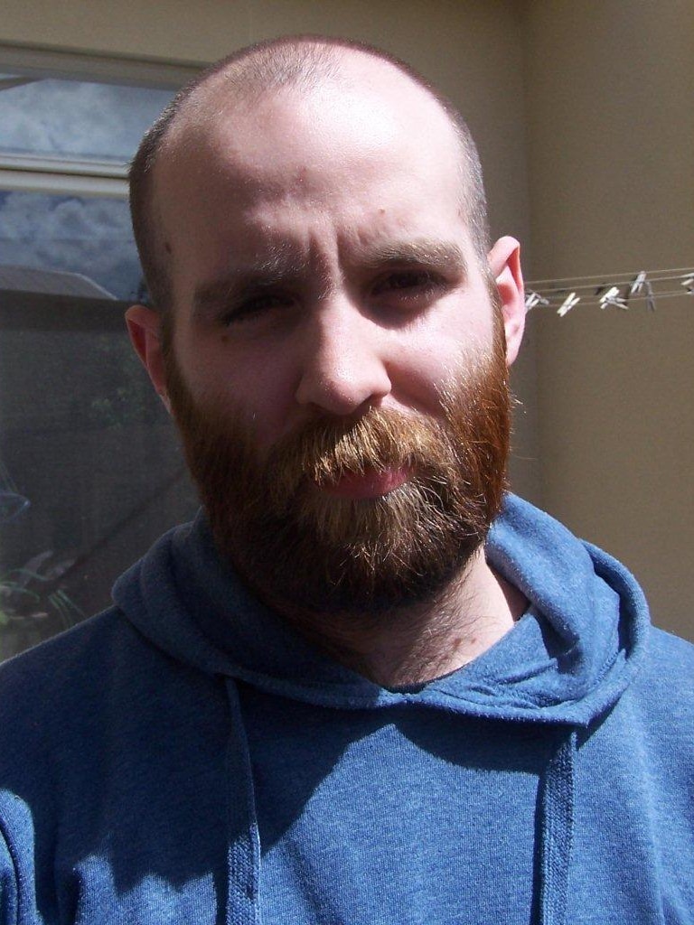 Man with a beard wearing a blue hoodie.