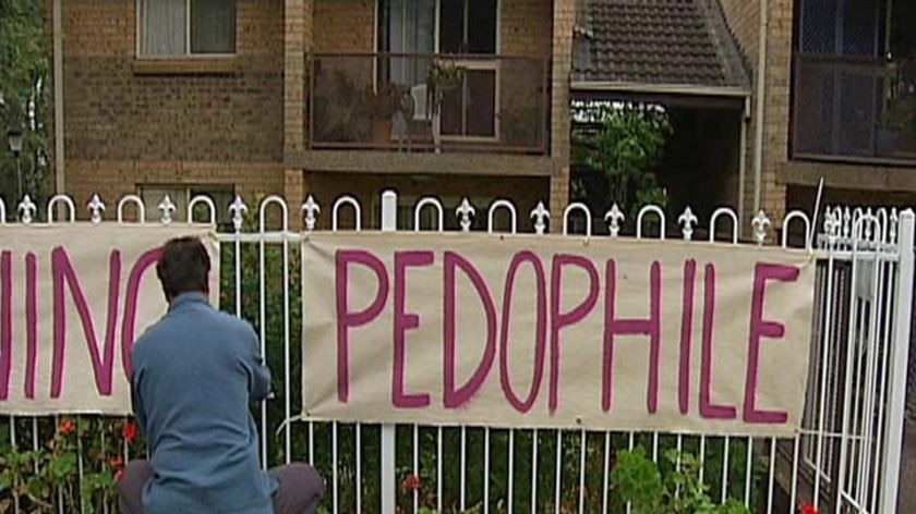 TV still of man hanging pedophile sign on fence outside Dennis Ferguson's unit in Sydney