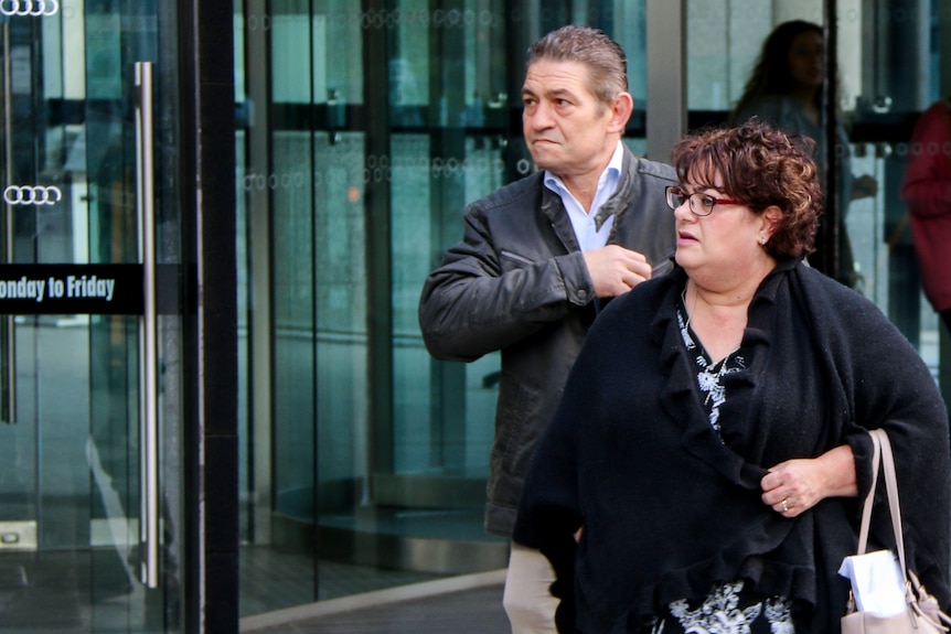 Barry Santoro. wearing black jacket and blue shirt, talks on phone outside federal court building.