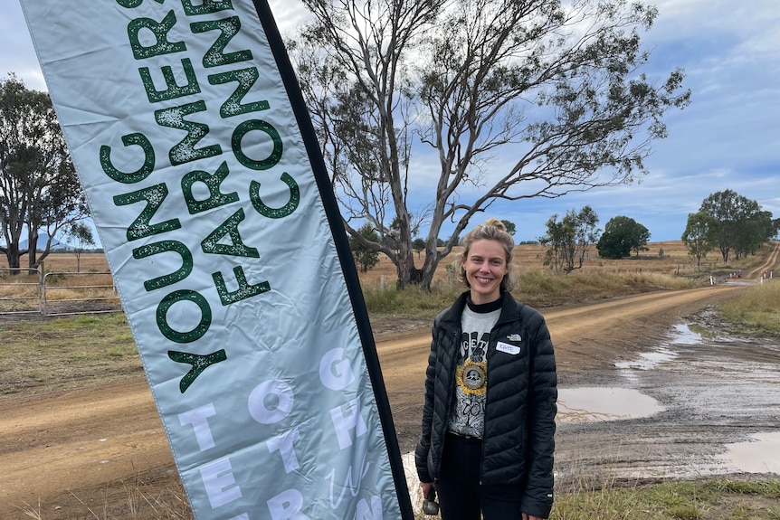 Photo of woman standing in front of sign reading 'Young Farmers Connect'