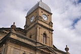 A town hall clock tower under a cloudy sky.