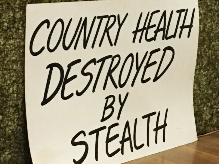 Sign reads 'county health destroyed by stealth'.
