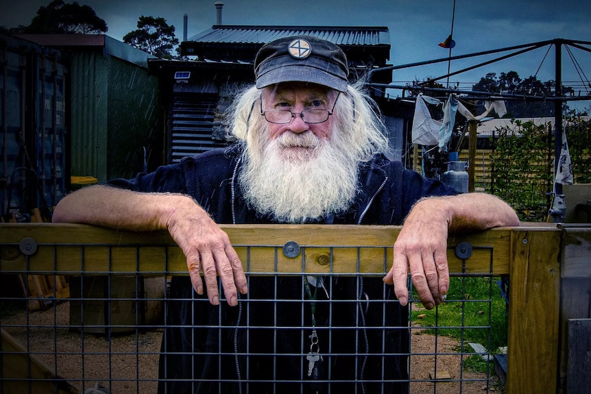 A man leaning on a fence
