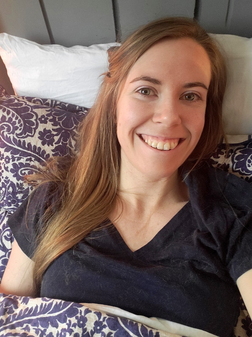 A woman smiles while resting on a pillow