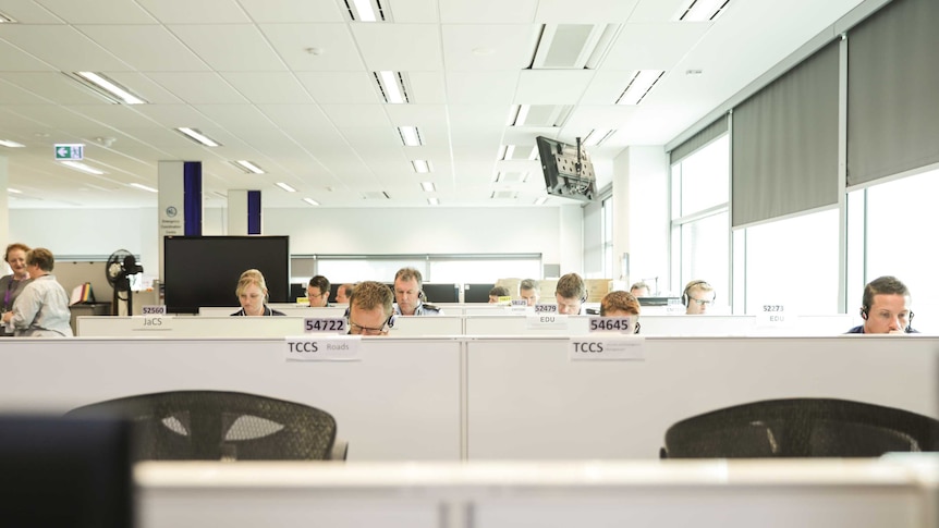 Office workers sit at desks, with only their heads showing above the desk dividers.