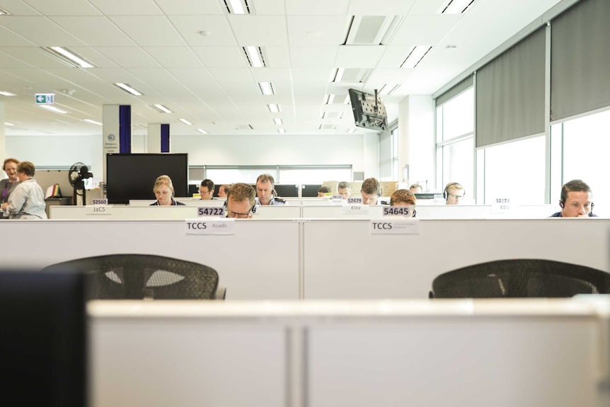 Office workers sit at desks, with only their heads showing above the desk dividers.