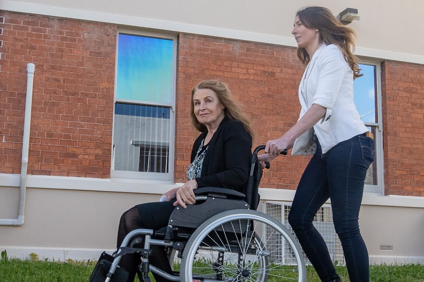 Sue Neill-Fraser in a wheelchair is wheeled by daughter into Highfield House.