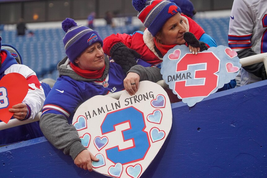 Buffalo Bills fans hold signs in support of Bills player Damar Hamlin.