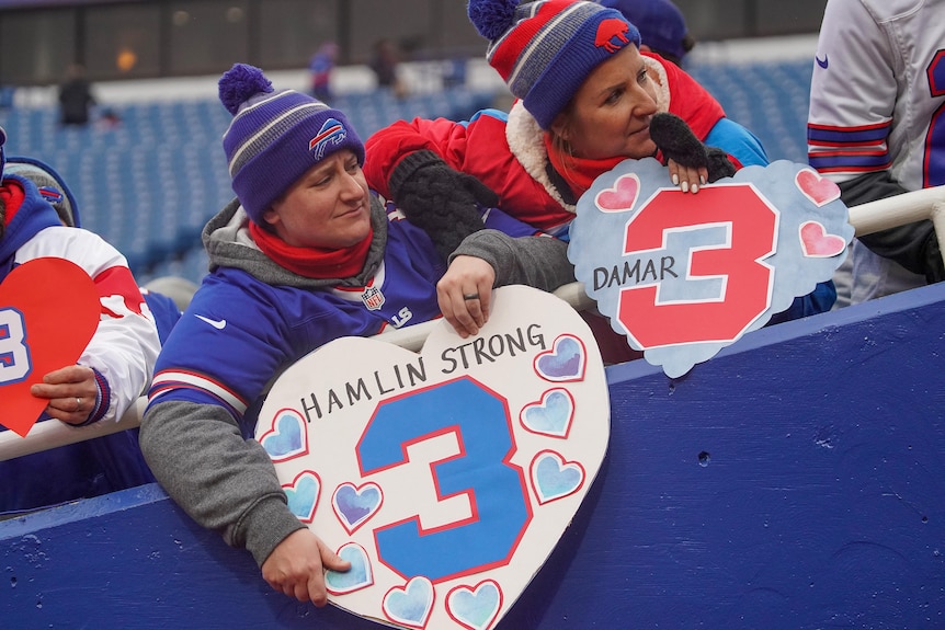Buffalo Bills fans hold signs in support of Bills player Damar Hamlin.