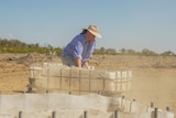 Jacque Hemming drags a feed container on her property near Dirranbandi, August 2023.