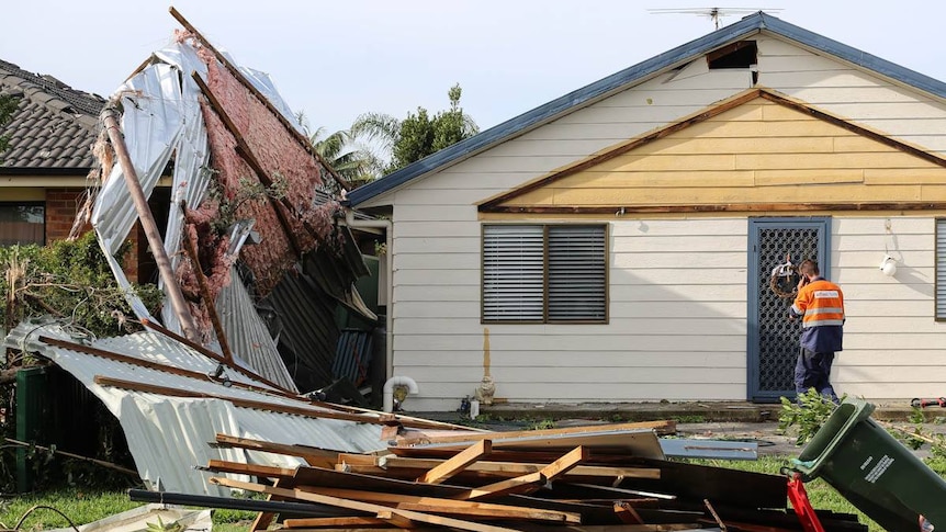 An SES worker approaches a house damaged during the storm that hit Kurnell.