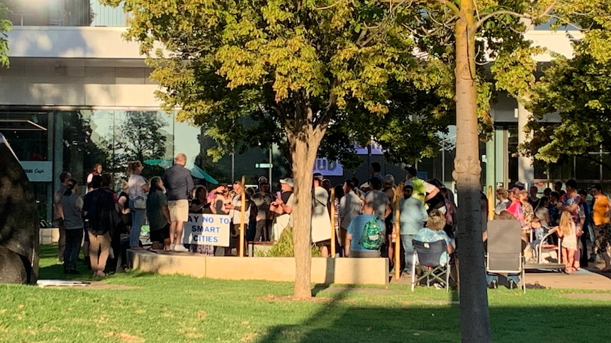 A group of people gathered outside a building, some holding signs 