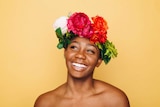 Closeup of woman smiling wearing flower crown with a bright yellow backdrop to represent simple skincare routines
