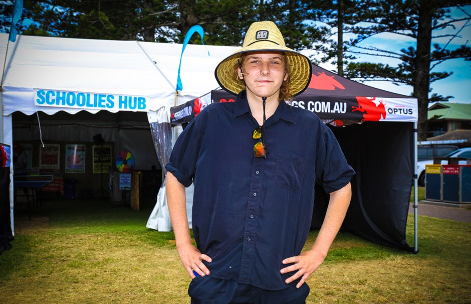 A young man wearing a straw hat standing in front of a marquee.