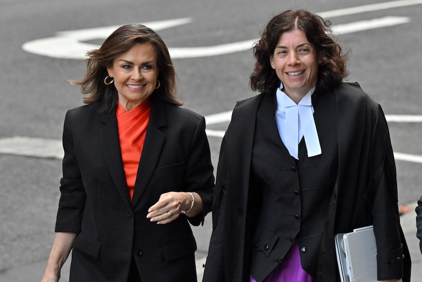 Two women in formal wear walk together.