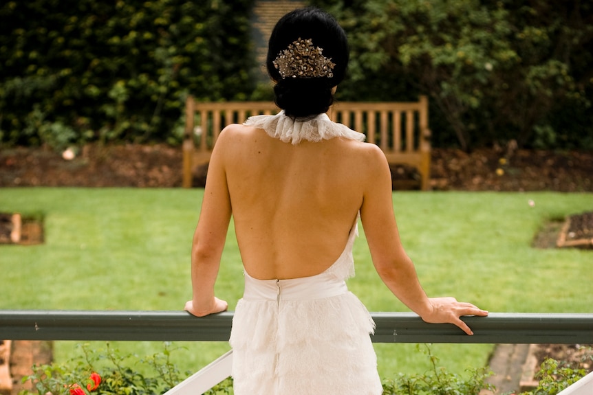 a woman wearing a bridal gown with her back to the camera