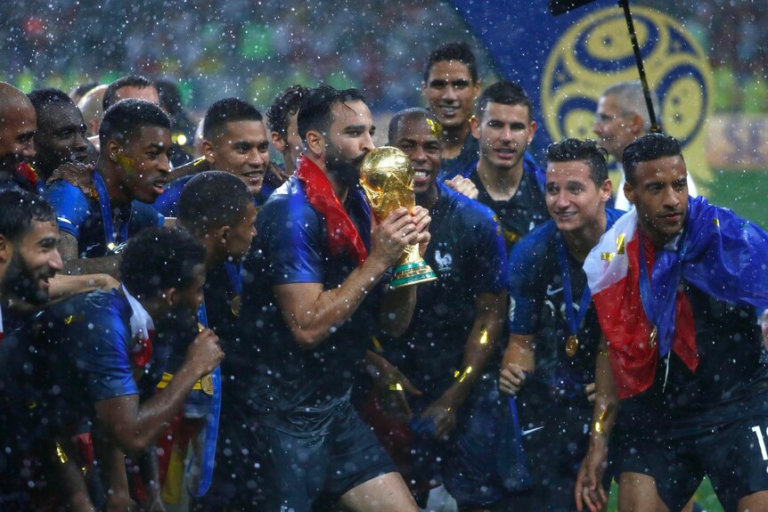 The French team celebrate with the World Cup trophy as confetti falls around them.