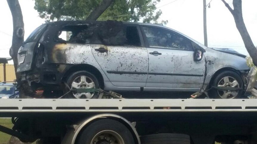 The burnt-out car on the back of a tow truck. The whole back section is charred and the back windows blown out.