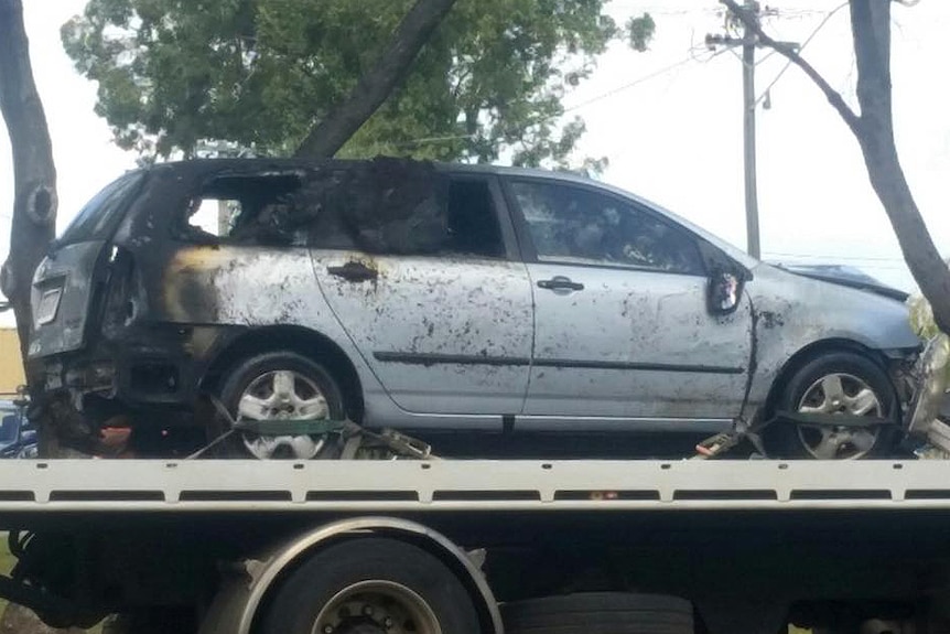 The burnt-out car on the back of a tow truck. The whole back section is charred and the back windows blown out.