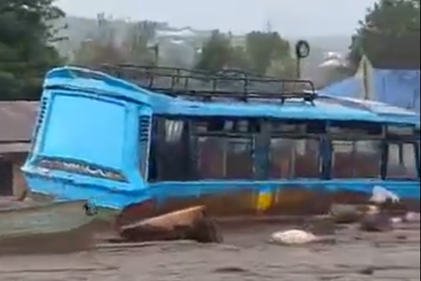 Screencrab from a video showing blue bus submerged by muddy flood waters. 
