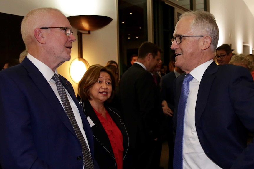 Justin Milne, Michelle Guthrie and Malcolm Turnbull stand together for a photograph at an evening function.