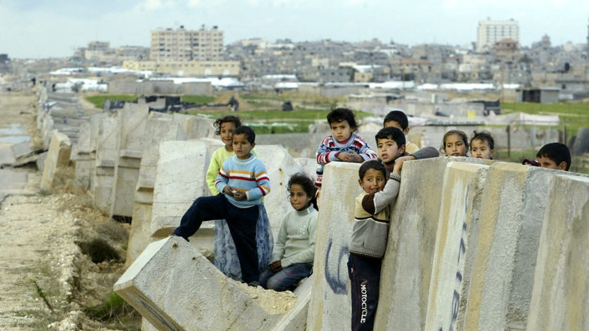 Palestinian children play at a breached border wall between Egypt and Gaza Strip