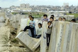 Palestinian children play at a breached border wall between Egypt and Gaza Strip