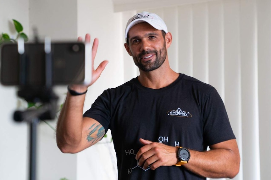 A man poses for a photo in front of a phone