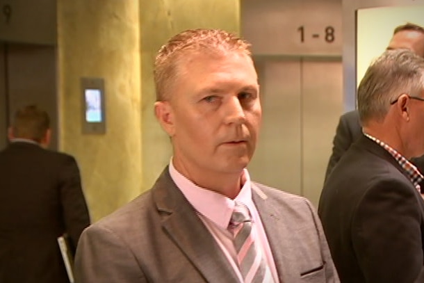 A man with short red hair stands in a building lobby