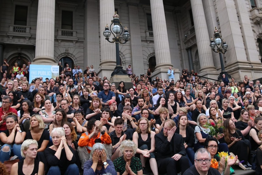 People gather on the steps of Parliament House in Melbourne for a vigil.