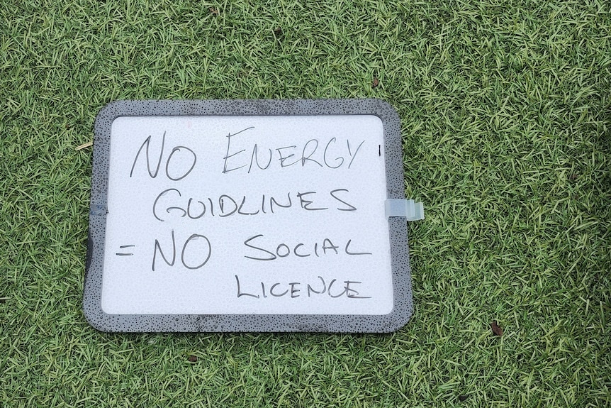 A sign saying "No energy guidelines = No social license" laid down in the grass