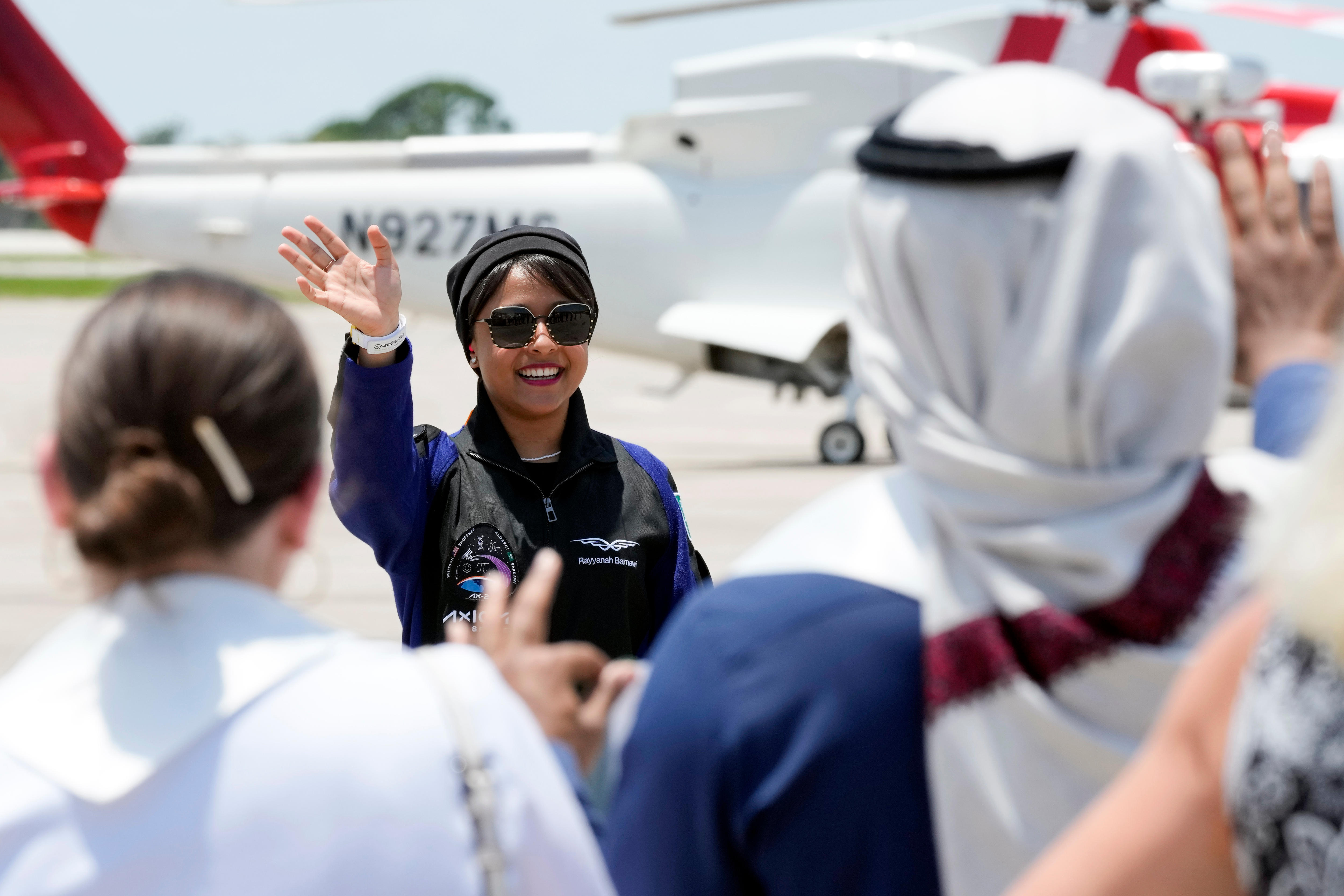 Saudi Arabian astronaut Rayyanah Barnawi waves to family and friends as she arrives at the Kennedy Space Center.