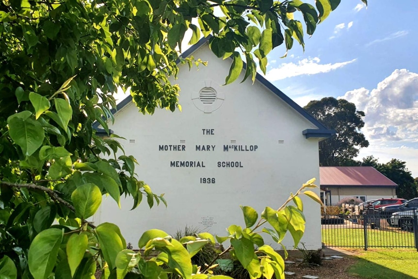 An old white building with the words "The Mother Mary MacKillop Memorial School 1938" on it.