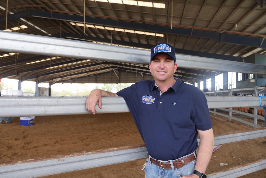  A man leans on a railing in front of show ring