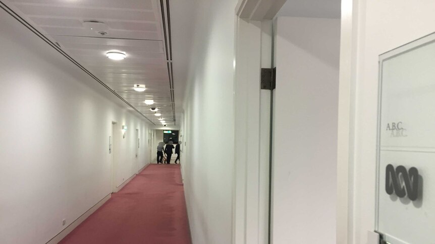 ASIO officers leave the Parliamentary Press Gallery corridor. Their faces are blacked out for legal reasons.