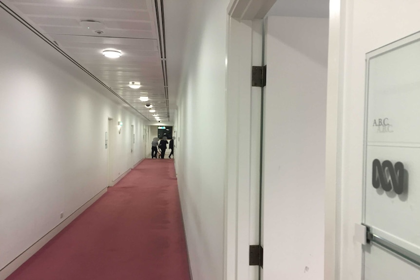 ASIO officers leave the Parliamentary Press Gallery corridor. Their faces are blacked out for legal reasons.
