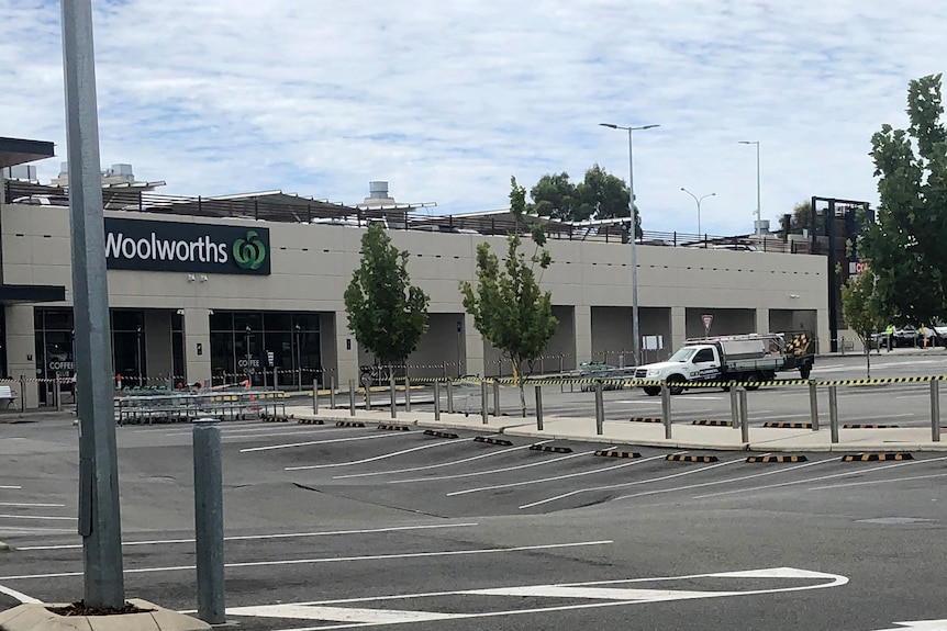 Red tape in the foreground cordoning off a shopping centre carpark.