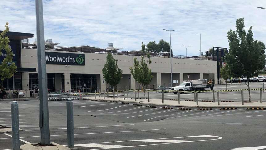 Red tape in the foreground cordoning off a shopping centre carpark.