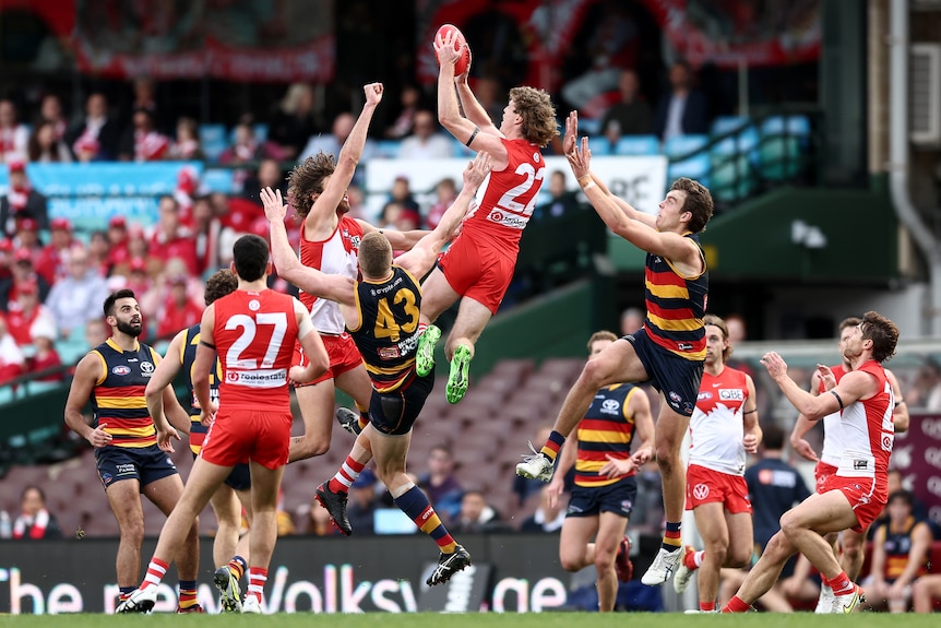 A Sydney AFL player leaps high and extends his hands to take a clean pack mark.