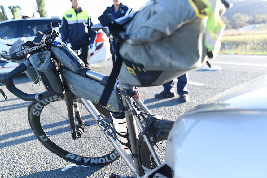 A bicycle wedged into the front of a car, with a bag attached.