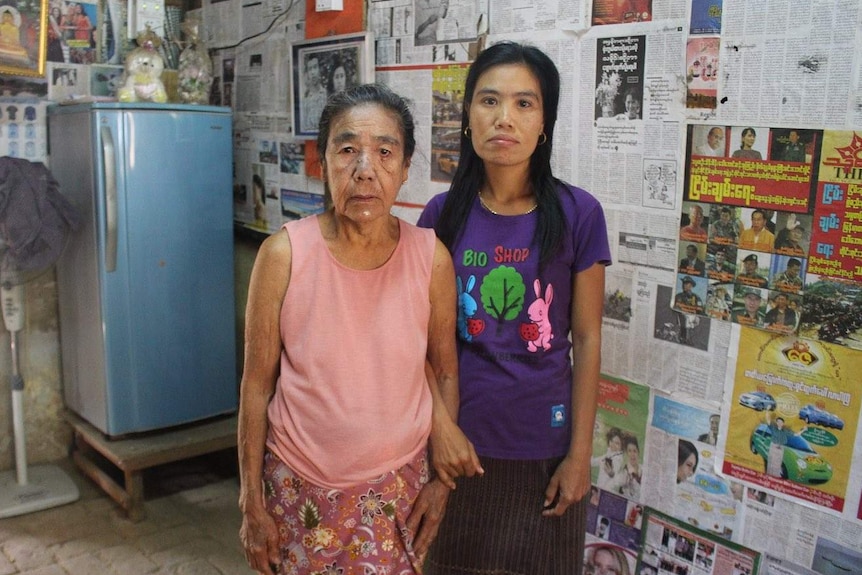 A mother and daughter stand in a room lined with newspaper.