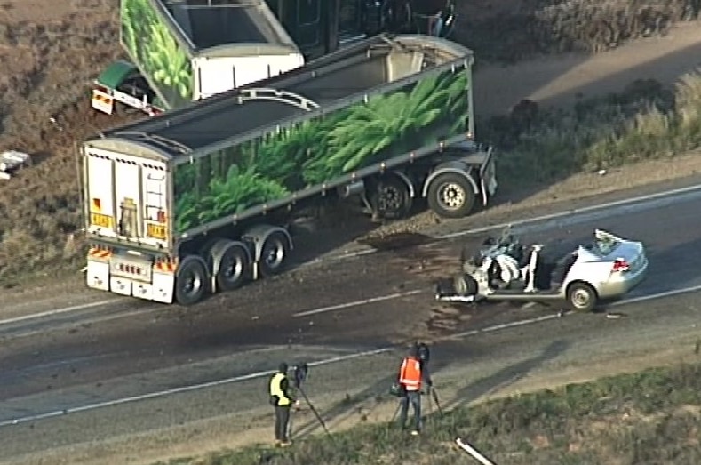 A green truck carriage on the side of a road and a silver car damaged on the road