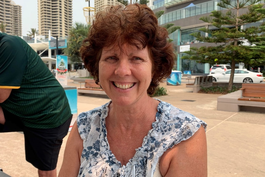 Julie Dahl smiles as she sits on a chair on a Gold Coast street.