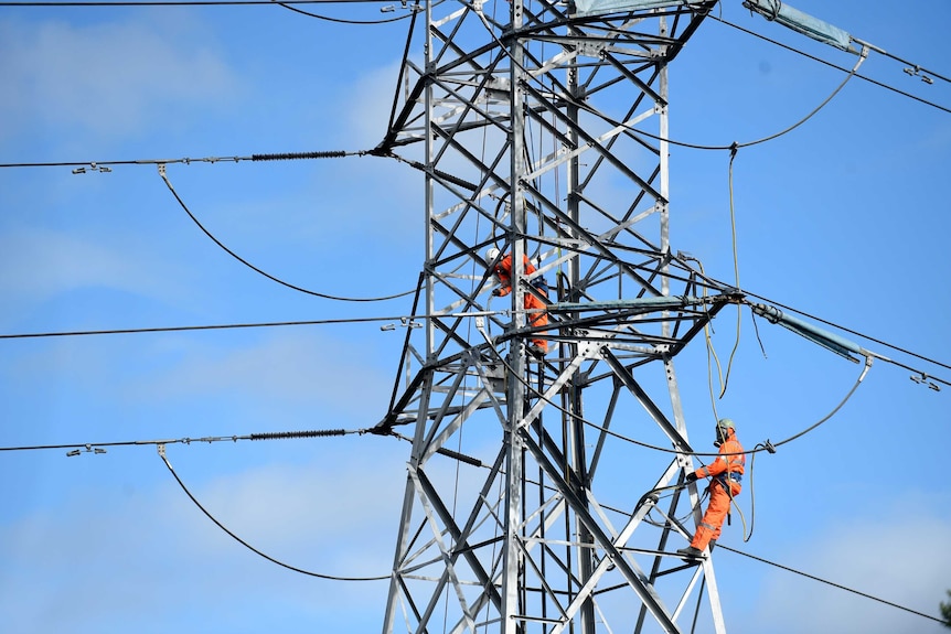Workers are seen high up on a pylon.
